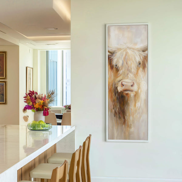 This vertical canvas print features a Highland cow with a soft, neutral palette and painterly style, displayed on a white wall with a bar and stools visible in the foreground.