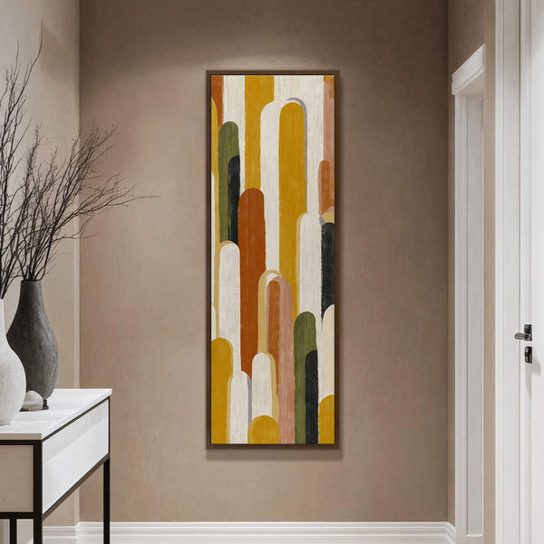 This vertical canvas wall art features an abstract pattern of rounded shapes in a warm palette of ochre, terracotta, and forest green, set against a taupe wall near a console.