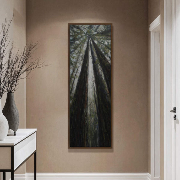This vertical canvas print captures a moody, impressionistic view looking up through dark redwood trees with a palette of deep greens and browns, set against a textured, taupe wall above.