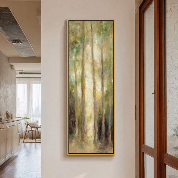 Vertical canvas wall art with an impressionistic forest scene in greens and yellows, framed in gold, hangs on a cream-colored wall next to a wooden door.