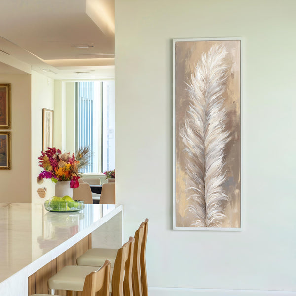 This vertical impressionistic painting print of a white feather in neutral tones is displayed in a white floater frame on a white wall beside a kitchen counter with stools.
