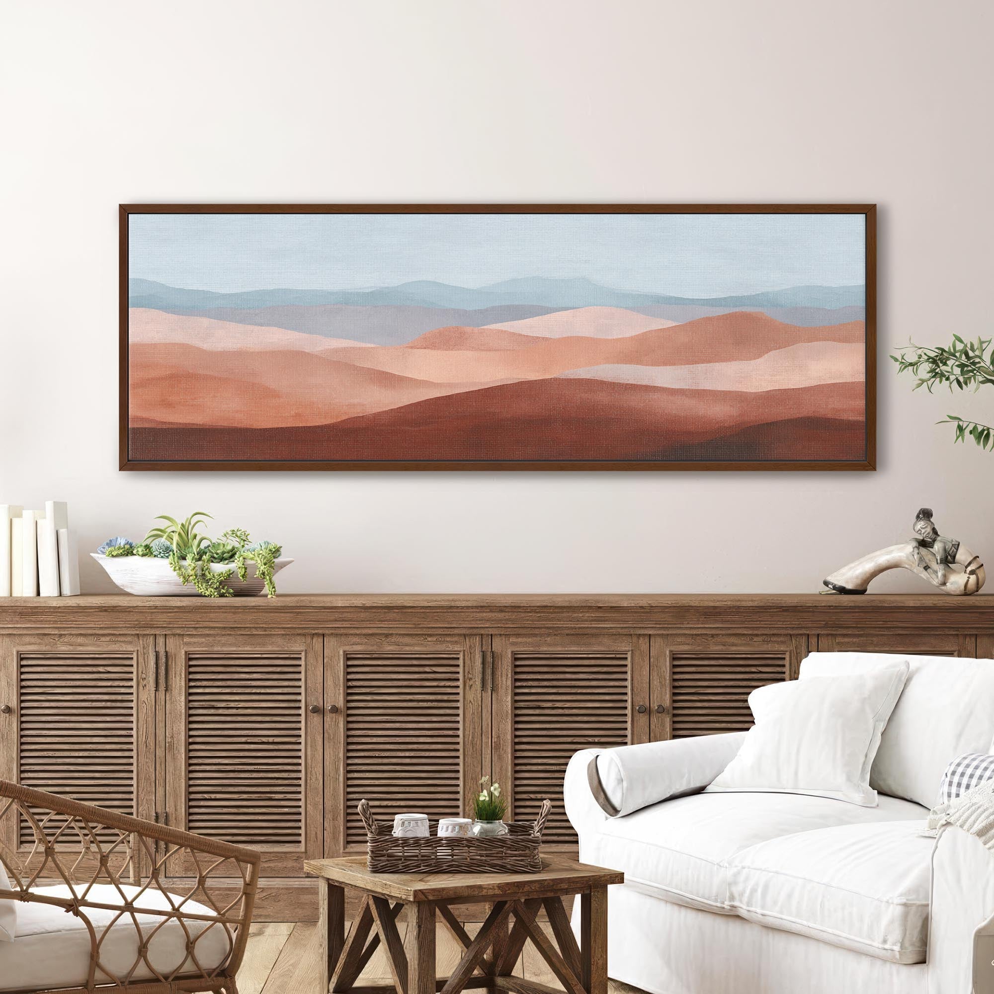 Framed desert landscape canvas wall art displayed above a rustic wood sideboard with white armchair in a cozy modern farmhouse living room
