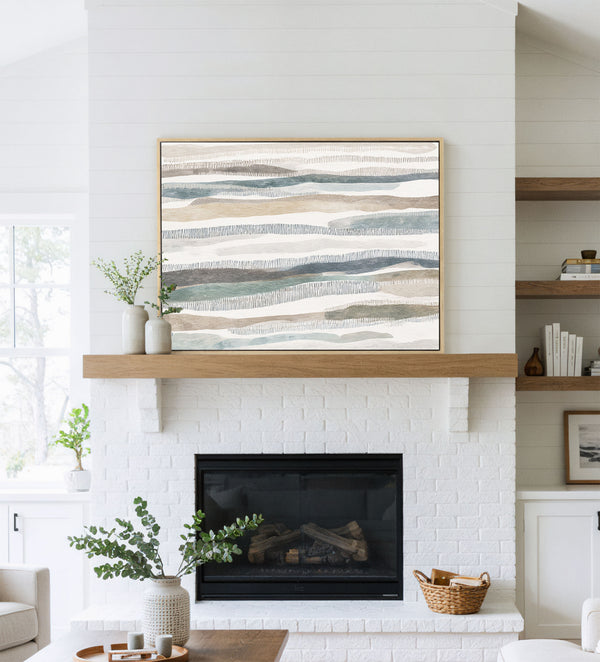 Large abstract art with horizontal bands of muted blues, browns, and grays hanging above a white brick fireplace.