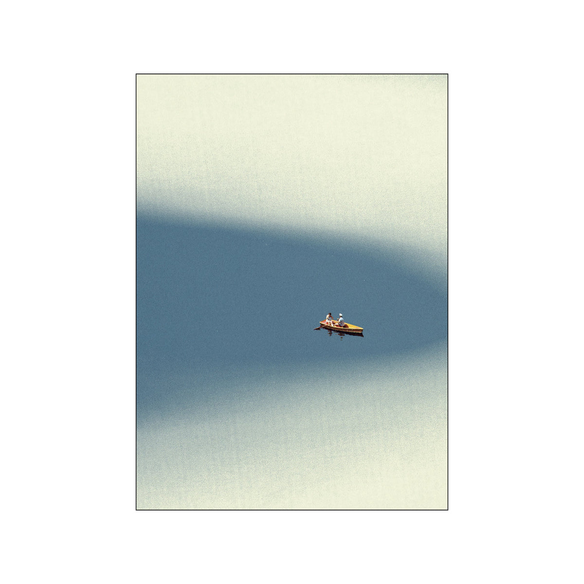 Small couple in a kayak floating on calm blue water beneath a soft white sky