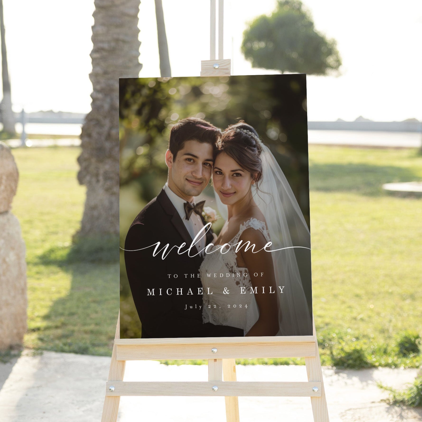 Wedding welcome sign with a couple's photo on an easel outdoors.
