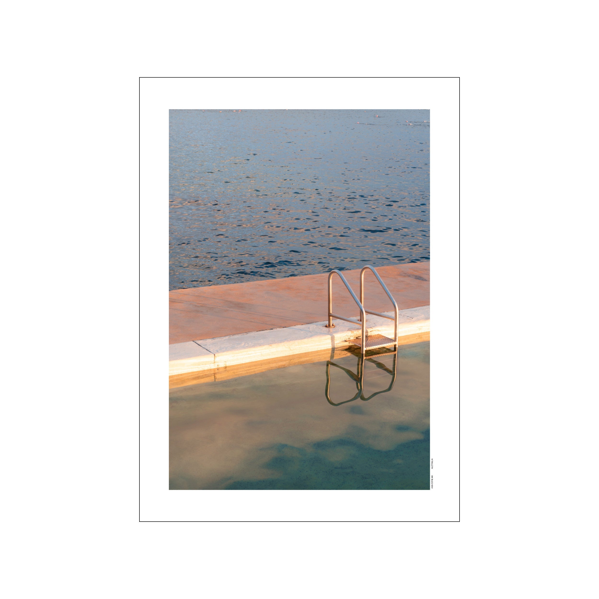 A close-up view of a swimming pool edge and ladder at sunrise, reflecting soft golden and blue light on the water's surface, perfect for a calming, modern, or coastal interior.