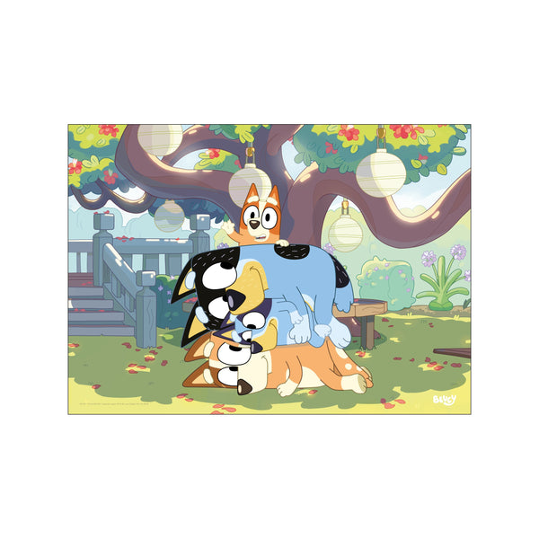 A whimsical illustration of three Bluey characters stacked together in a playful pile in a garden setting, with a large tree adorned with lanterns overhead.